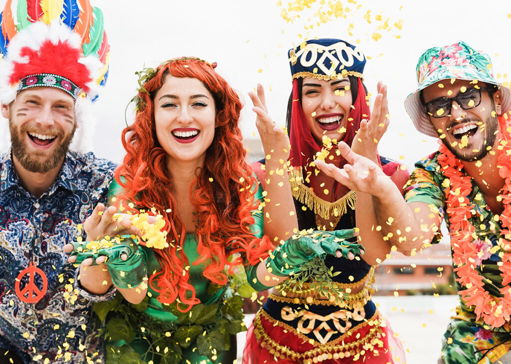 grupo com quatro pessoas felizes vestidas com fantasias e jogando confetes