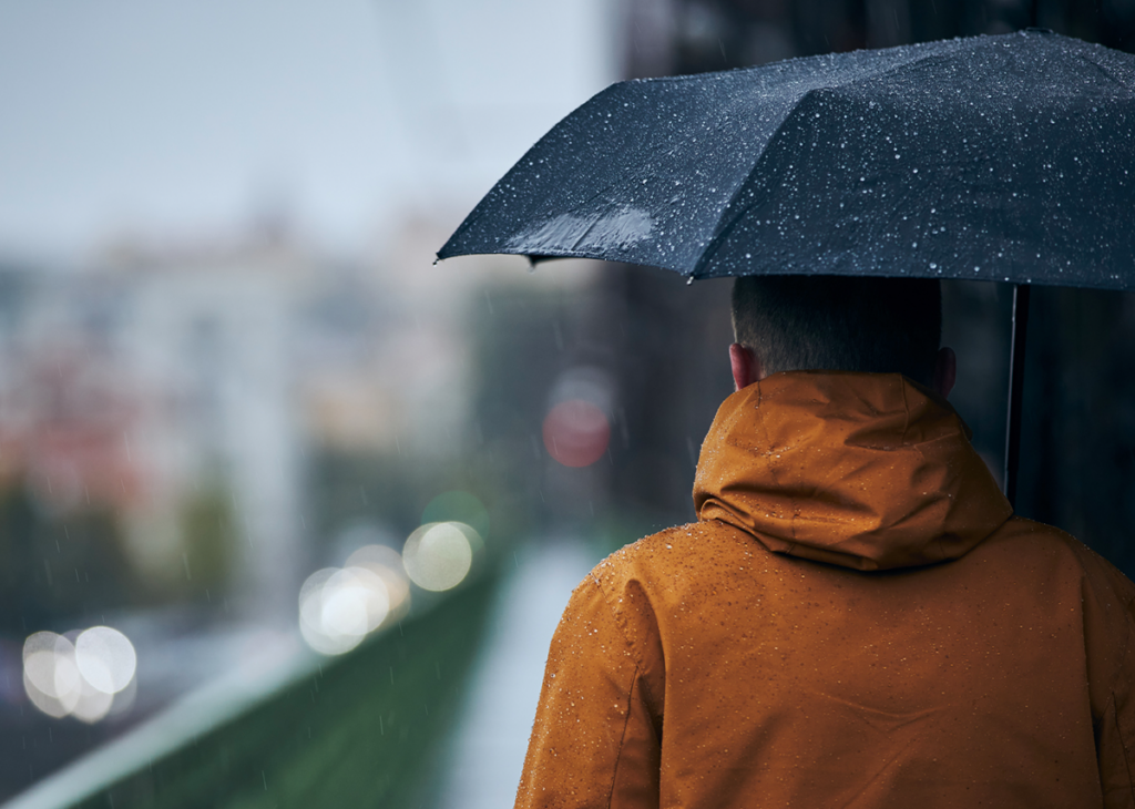homem com capa de chuva eguarda-chuva