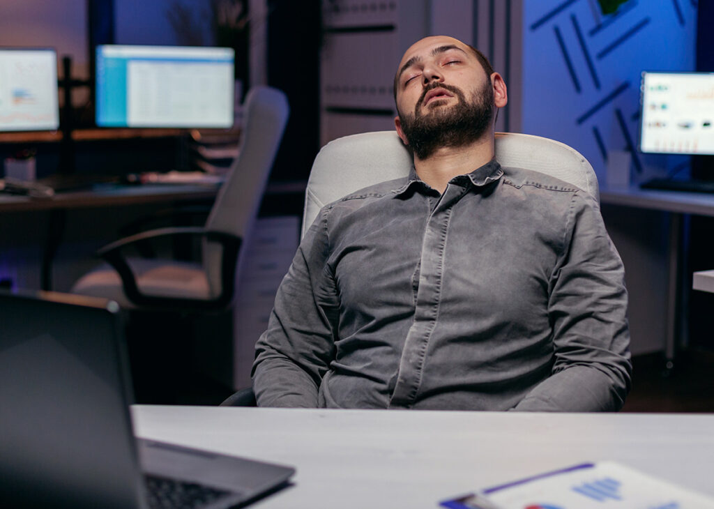 homem exausto dormindo no escritório