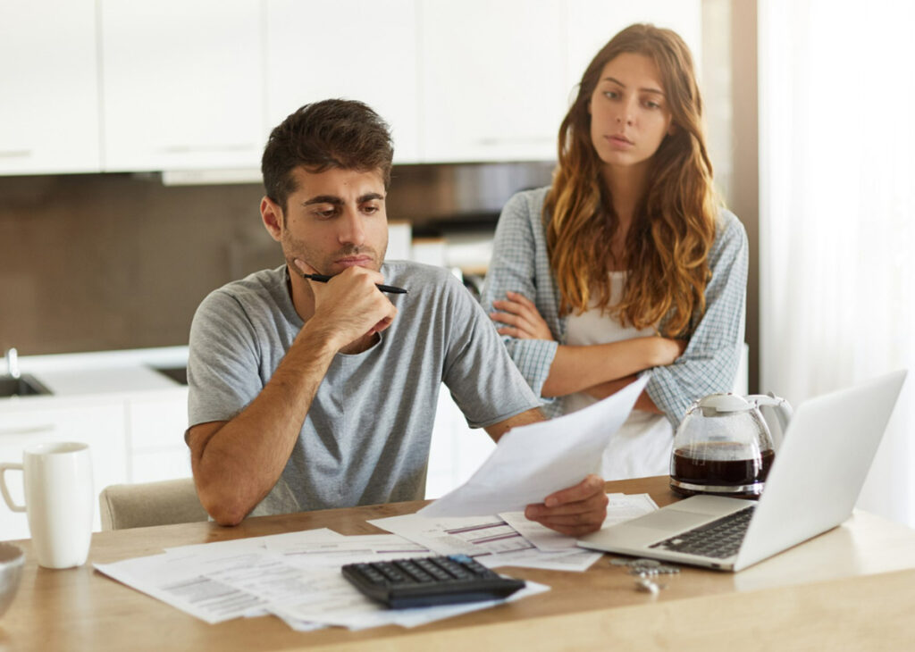 casal preocupado fazendo contas com calculadora e computador